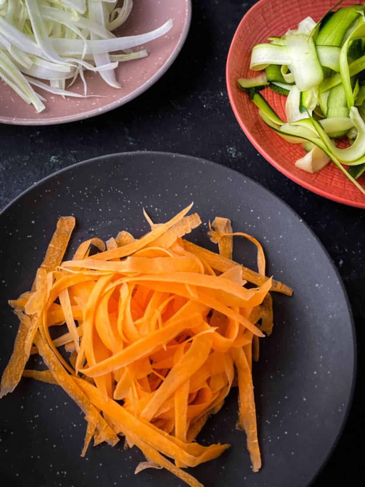 plate of grated carrots next to plates of grate fennel and cucumber