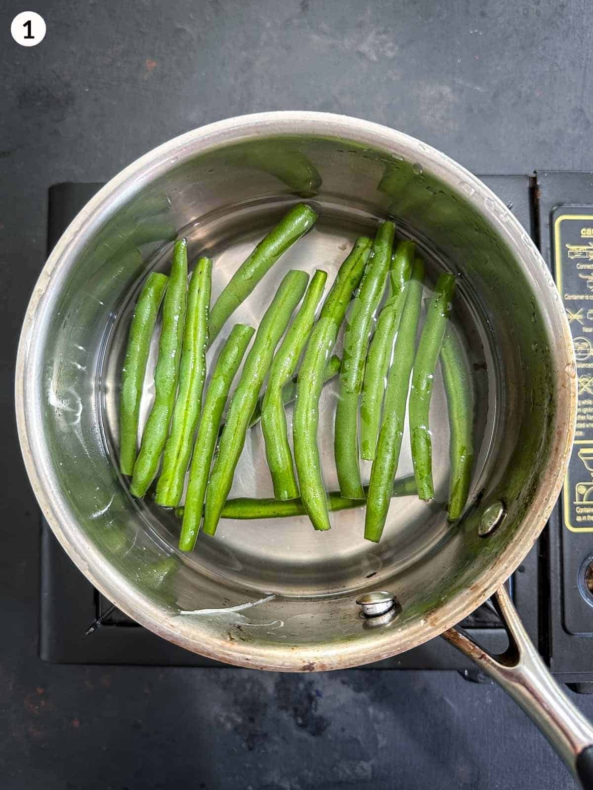 blanching green beans on a pot of water on a stove top