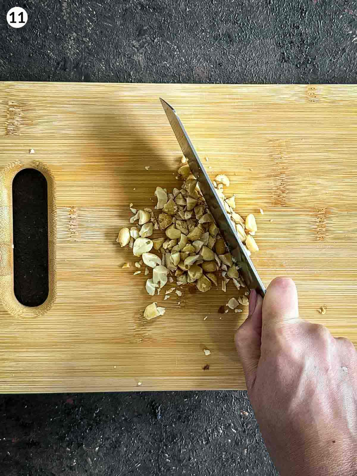 Chopping peanuts with a knife on a wooden board