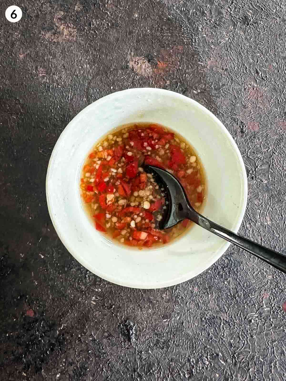 Bowl of chilli fish sauce dressing with a black spoon