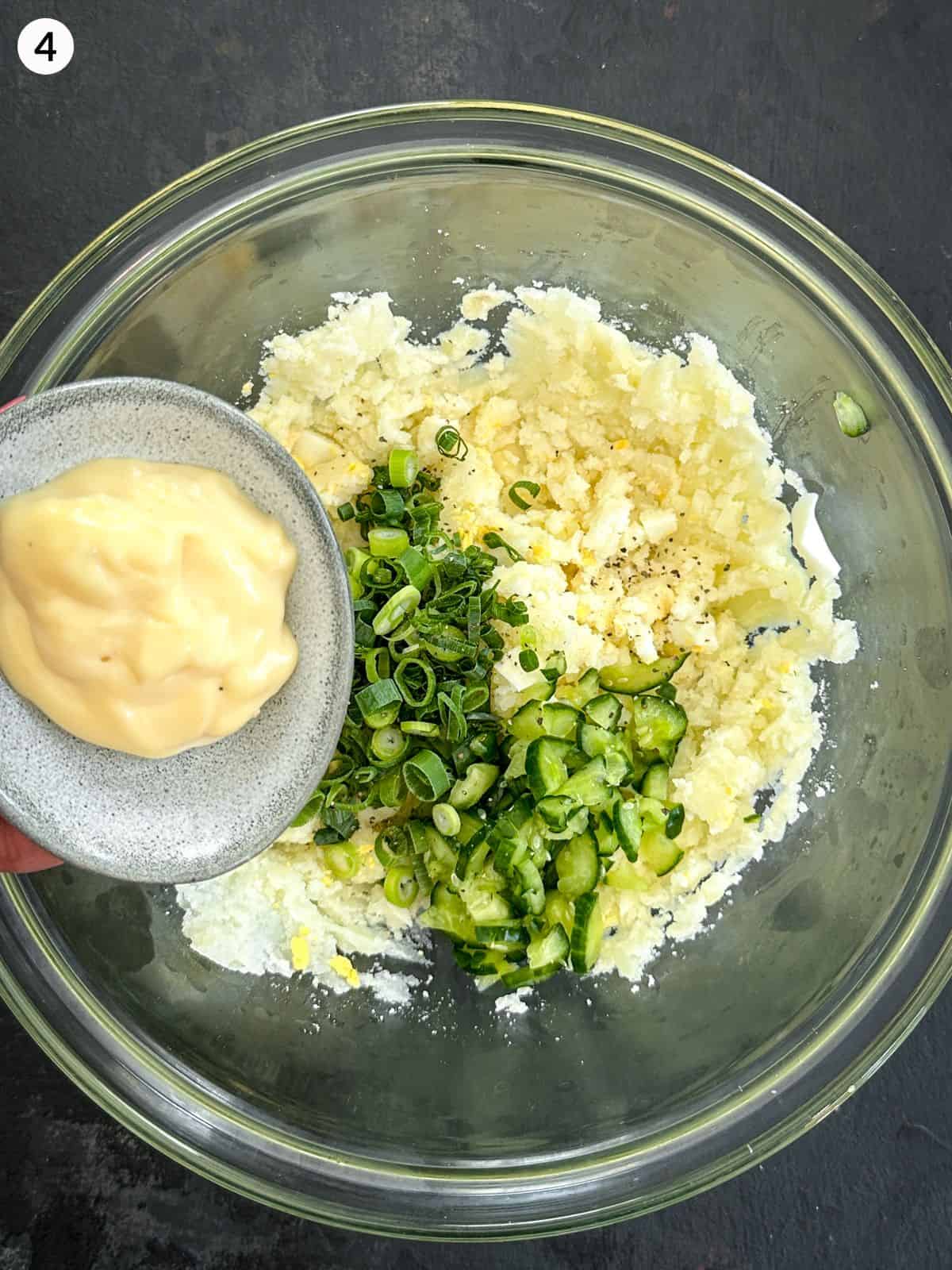 Adding mayonnaise to Korean mashed potato ingredients in a glass bowl