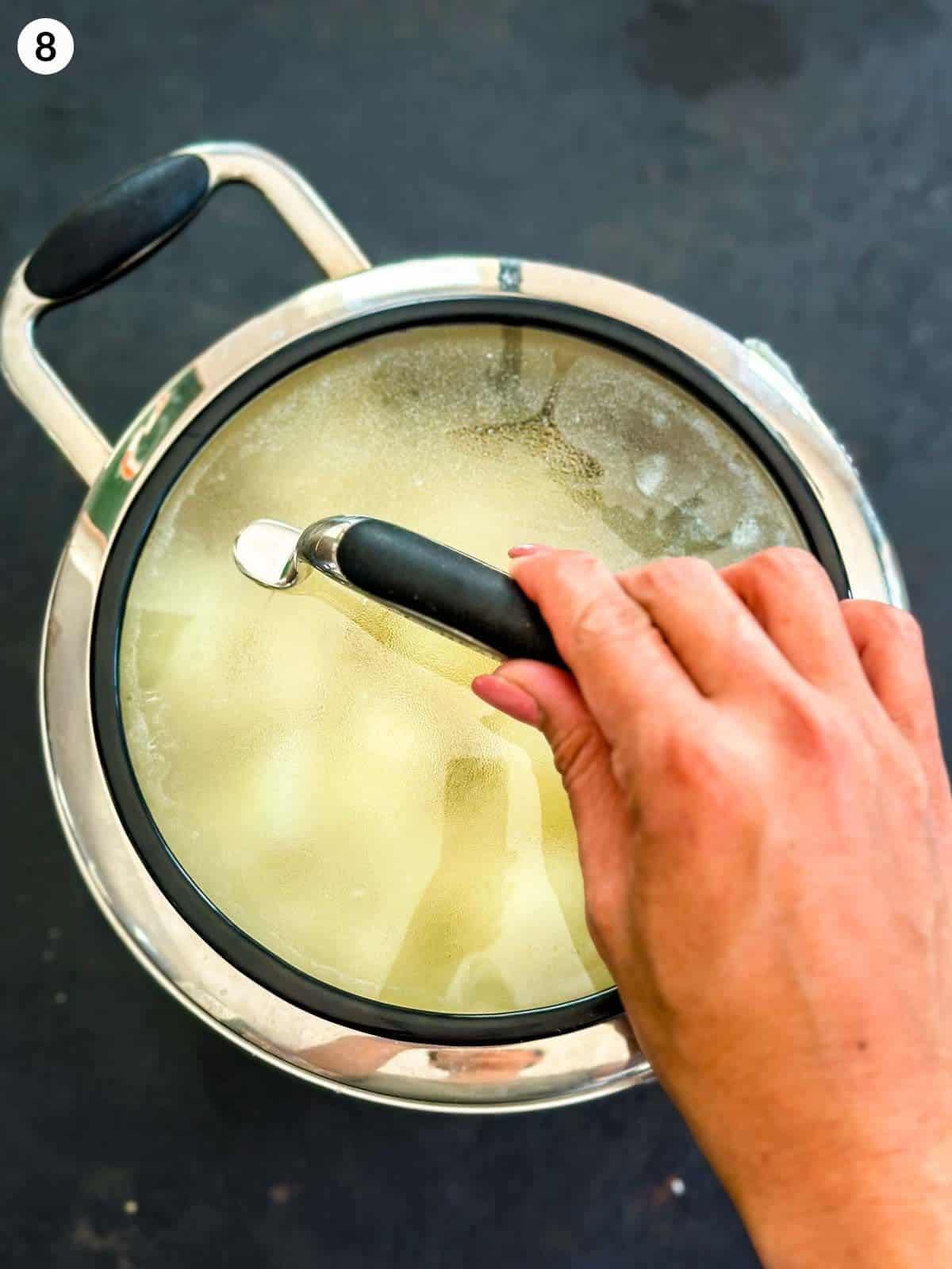 Covering a pot of cooked potatoes with a lid