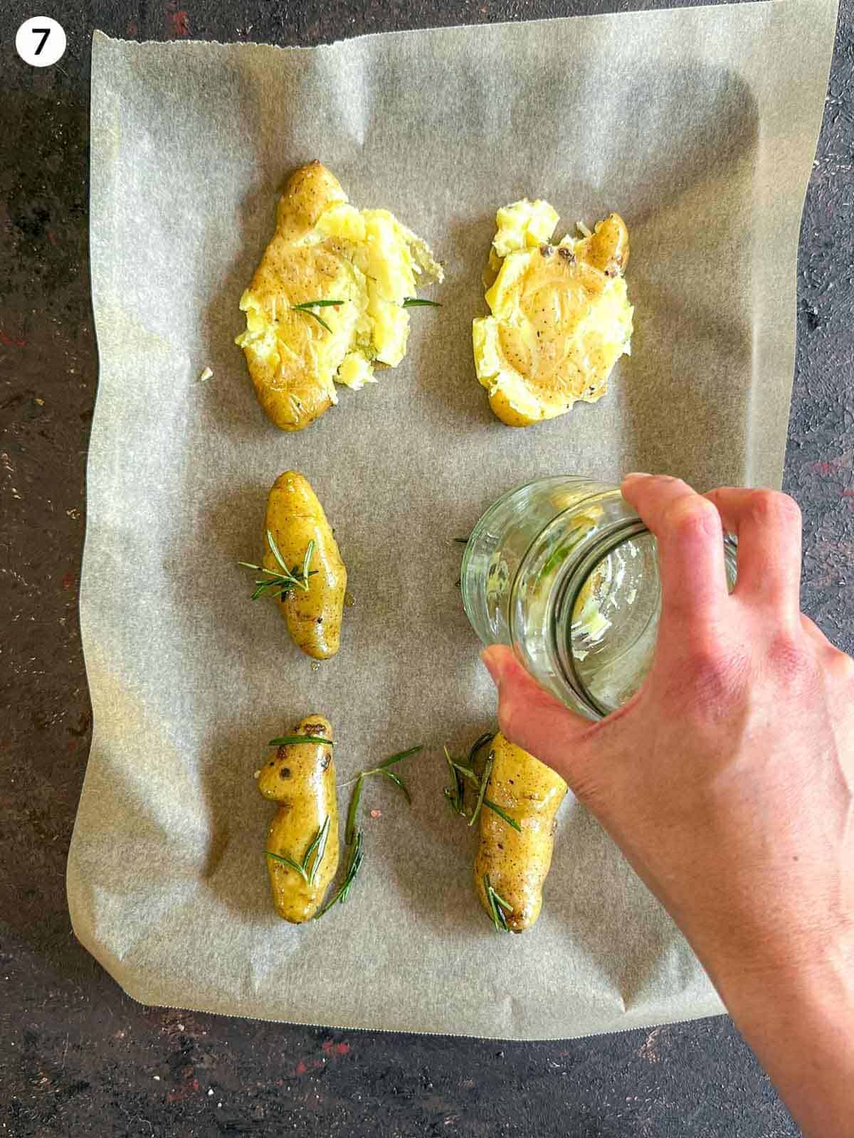 Smashing fingerling potatoes with the bottom of a jar, evenly laid out on parchment paper on a sheet pan