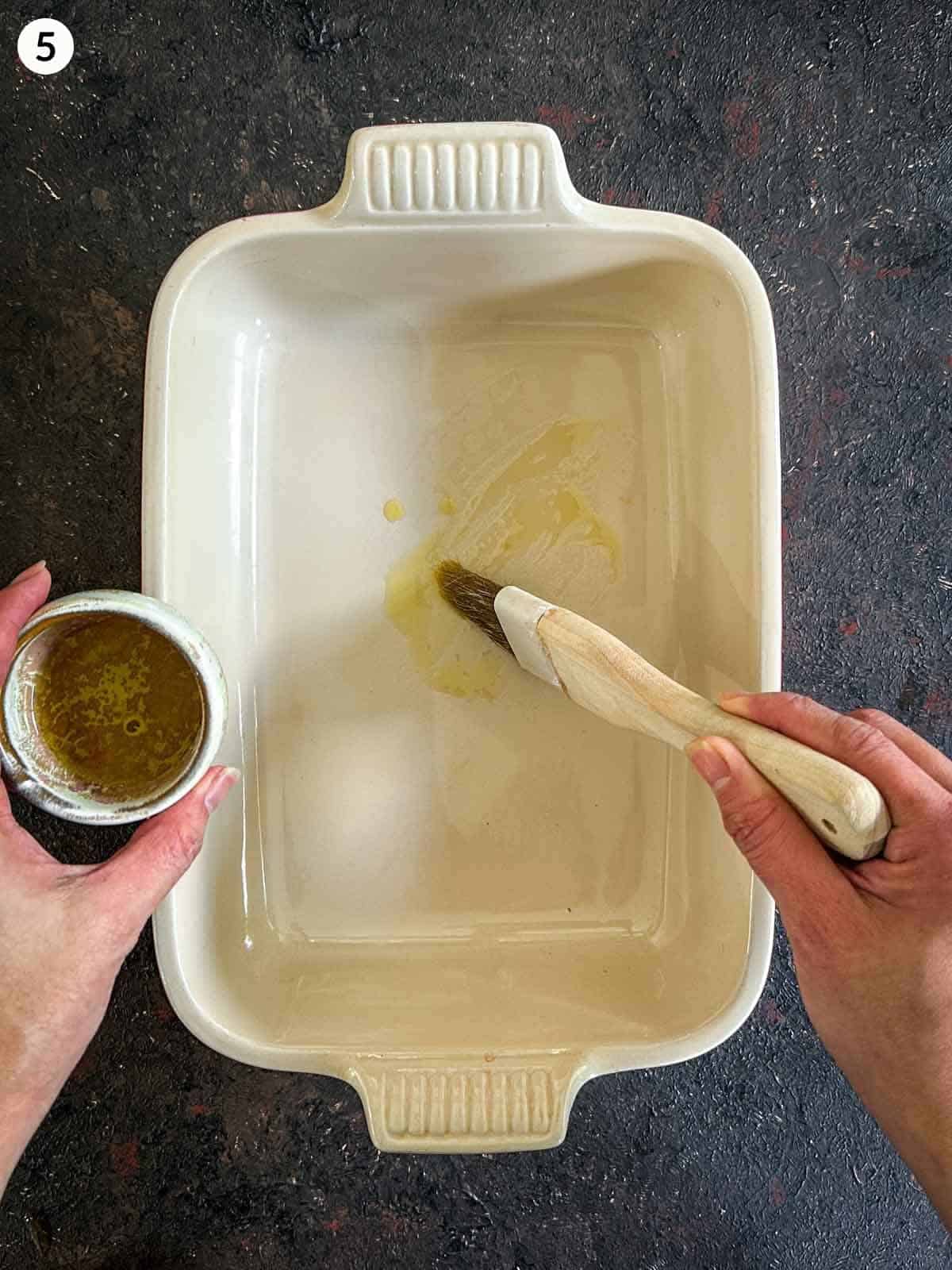 Basting olive oil on a baking dish with a basting brush