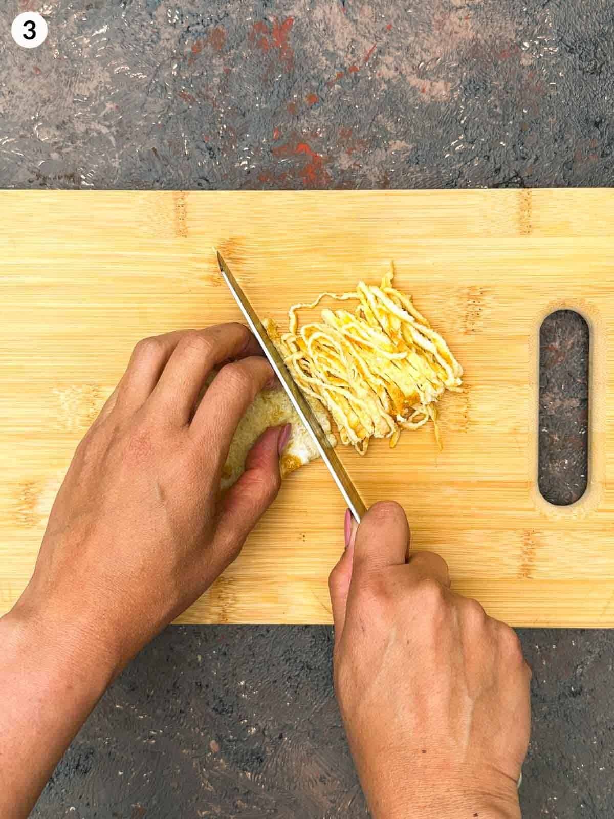 Slicing omelette with a knife on a wooden board