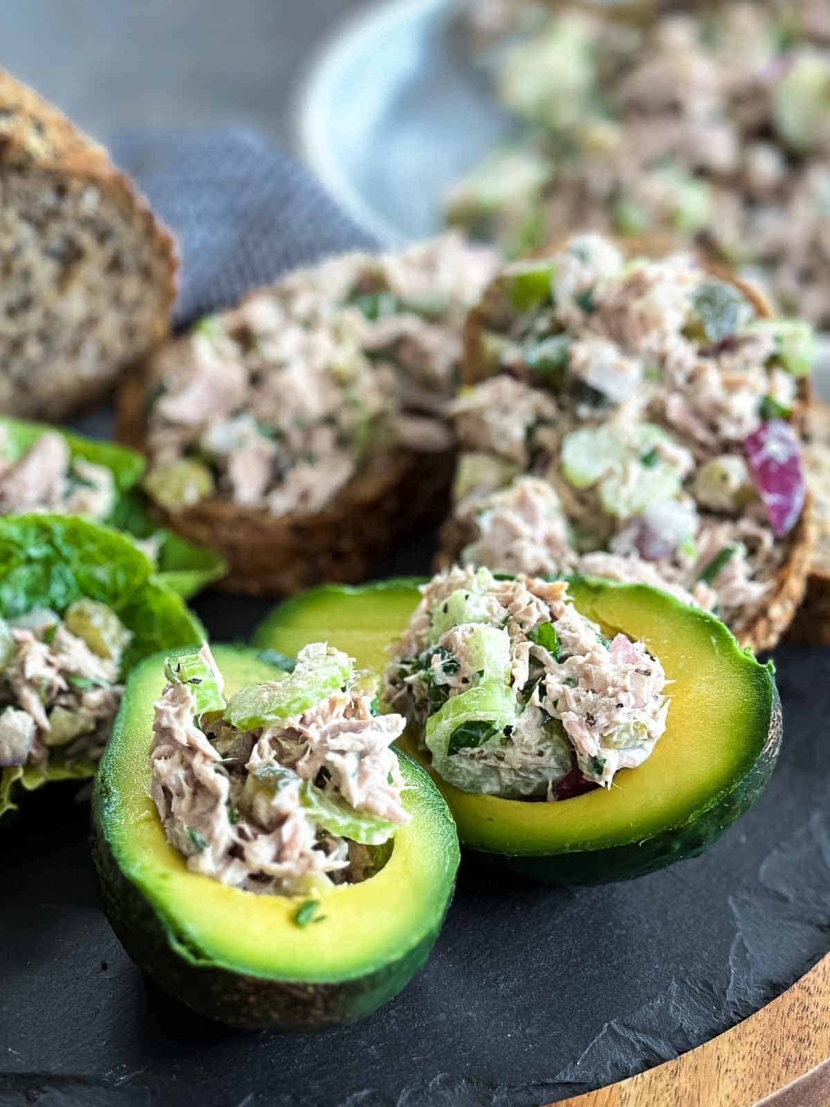 Healthy tuna salad on avocado halves on a slate wooden board