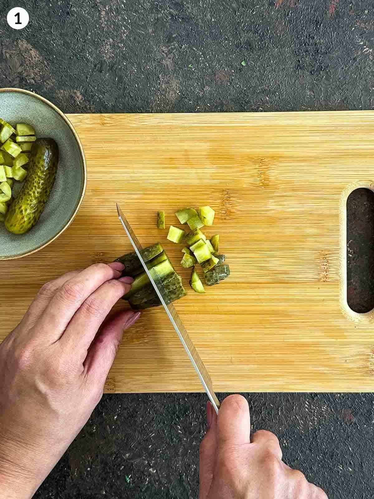 Chopping dill pickle on a wooden board with a knife