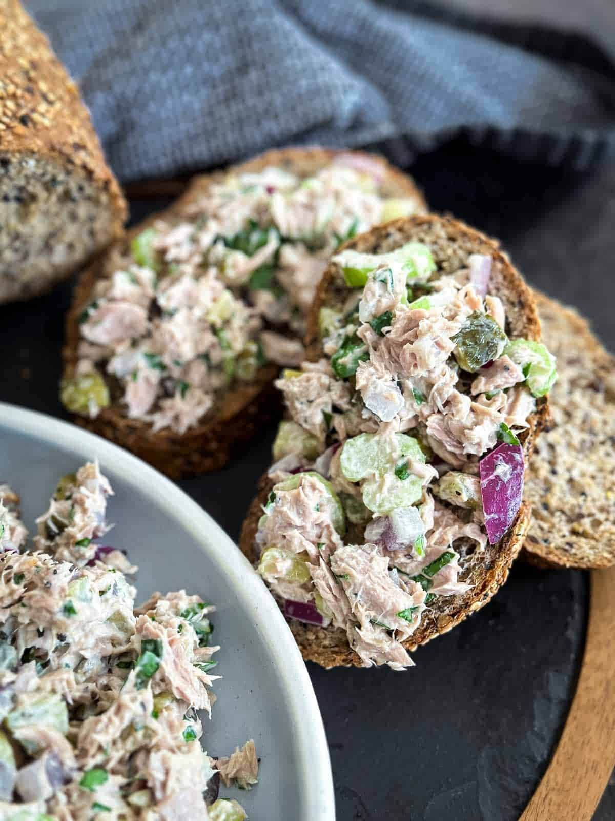 Healthy tuna salad on slices of bread on a slate board