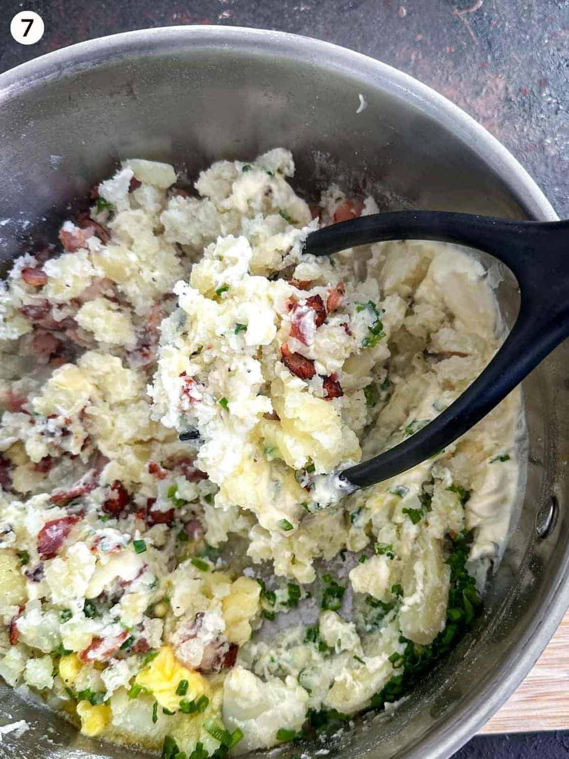 Mashing potatoes with a masher in a mixing bowl