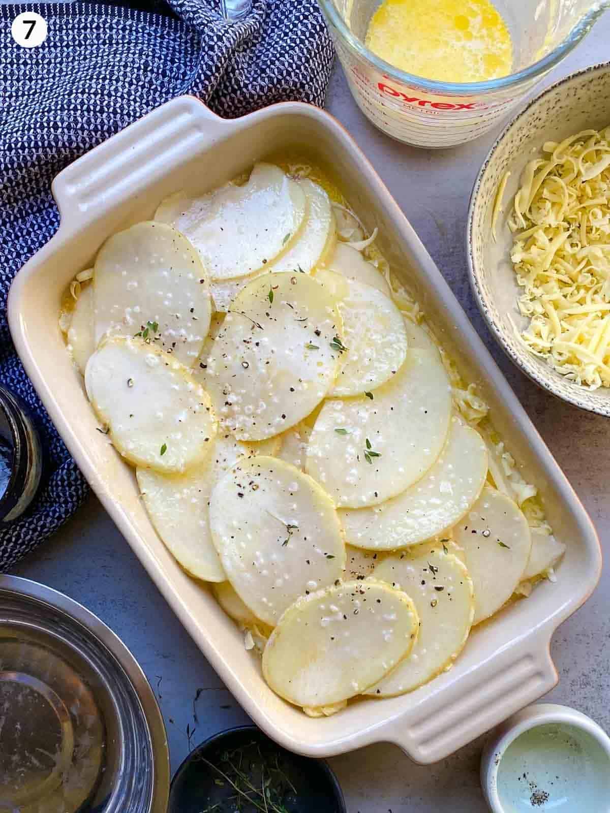 Layers of potatoes with salt and cheese in a ceramic side dish