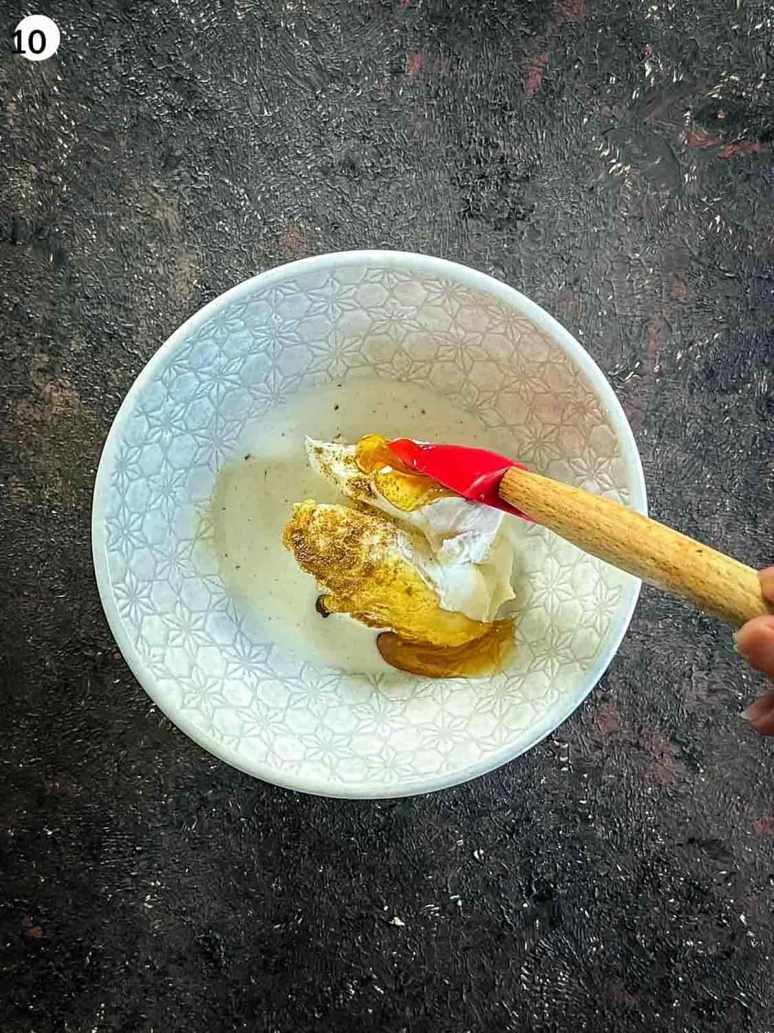 Mixing flavoured quark cheese with a red spatula in a small white bowl