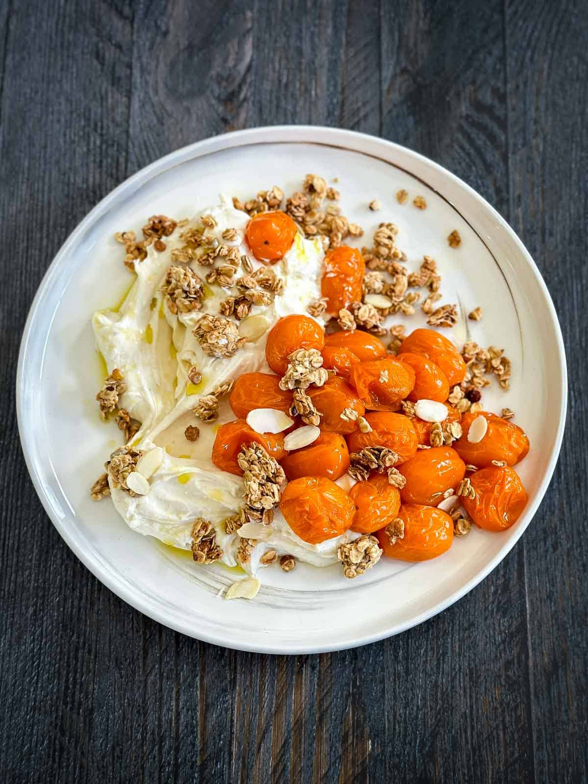 Roasted Grape Tomatoes on Quark on a marbled plate on a wooden background