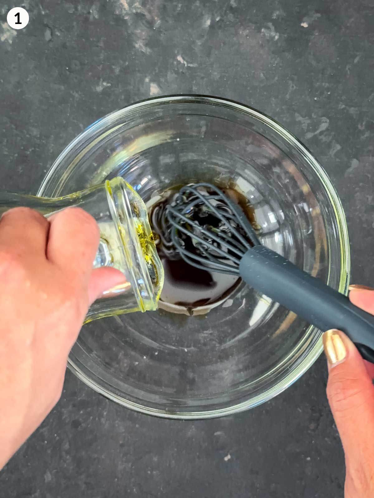 Whisking olive oil with balsamic vinegar in a clear bowl