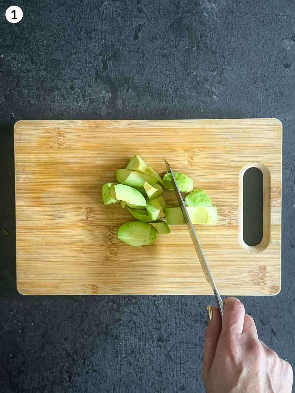 Chopping avocado on a wooden board with a knife