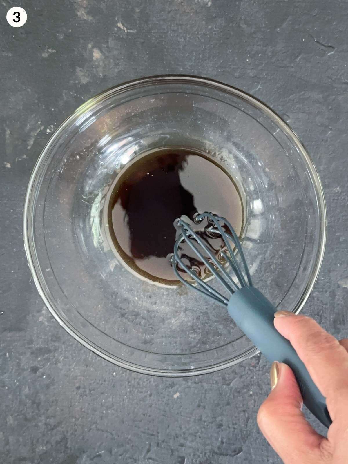 Whisking olive oil and balsamic vinegar in a clear mixing bowl