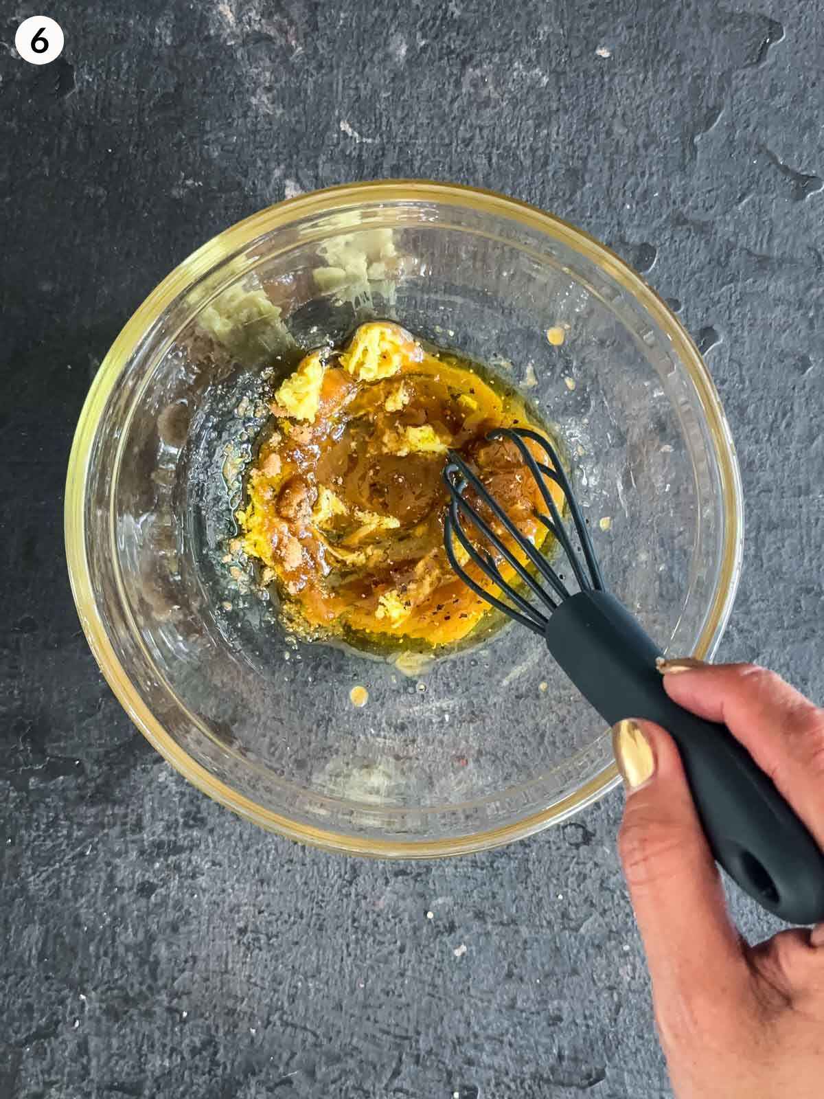 Whisking the ingredients for Ginger Salad Dressing with Tamarind in a clear mixing bowl with a whisk