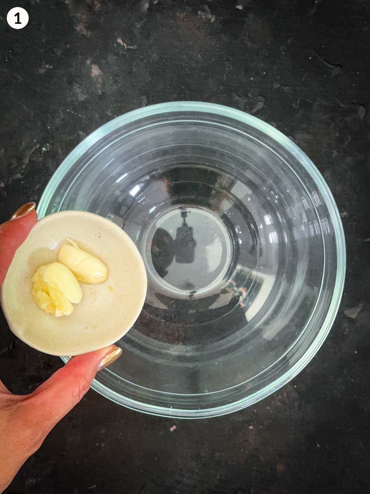 Adding whole garlic cloves into a clear bowl