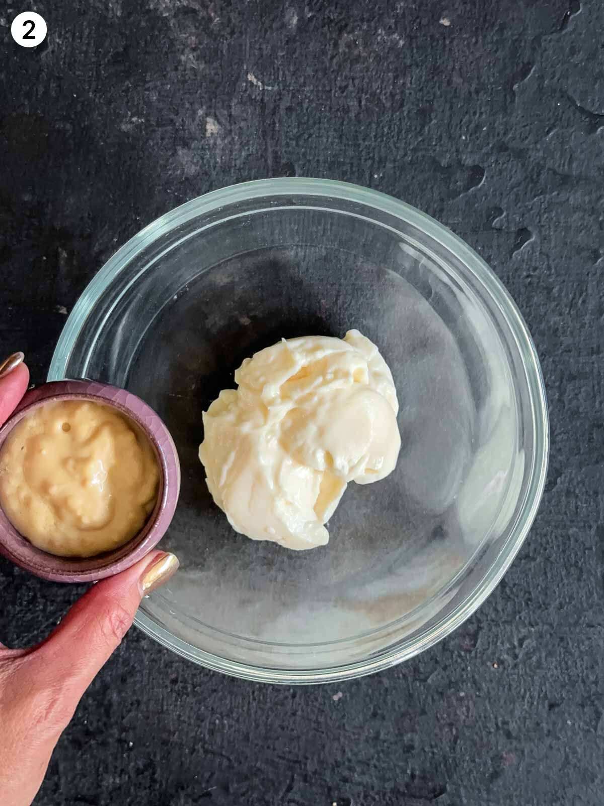 Adding horseradish cream to a clear mixing bowl with mayonnaise