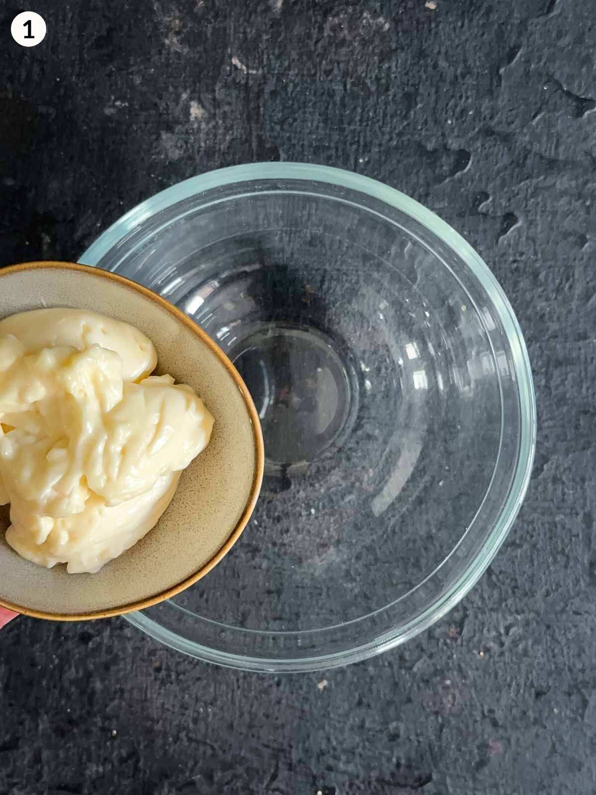 Adding mayonnaise to a clear mixing bowl