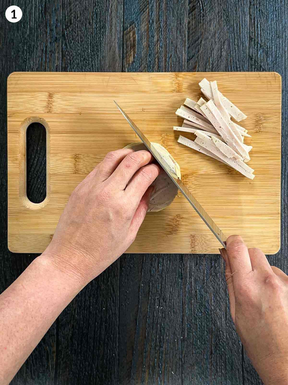 Cutting Vietnamese ham on a wooden chopping board with a knife