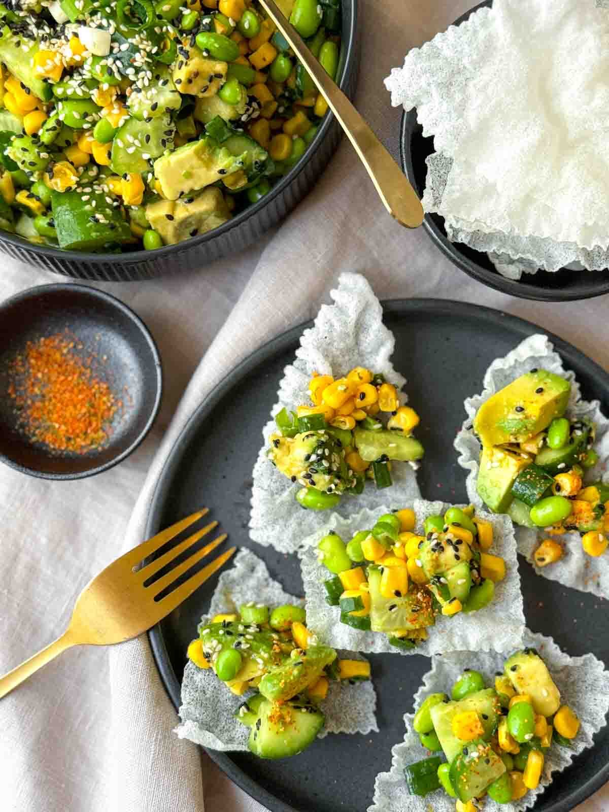 Individual serves of Cucumber Edamame Salad on deep fried rice paper with a bowl of the salad on the side