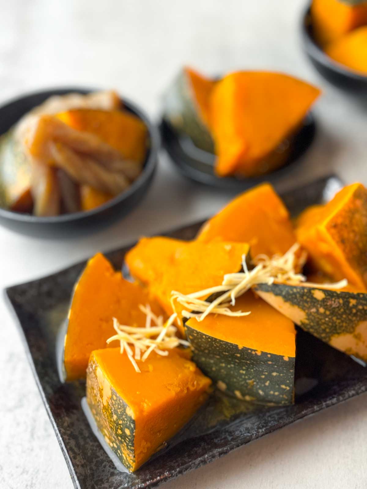 Simmered Japanese Pumpkin in a rectangle plate with another serve in a bowl in the background