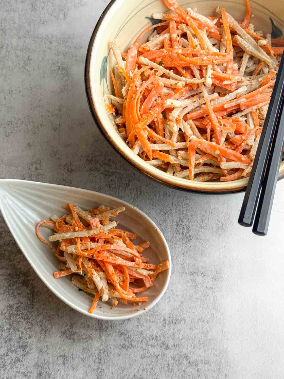 2 serves of Japanese Burdock Root Salad with a black pair of chopsticks resting on the large bowl