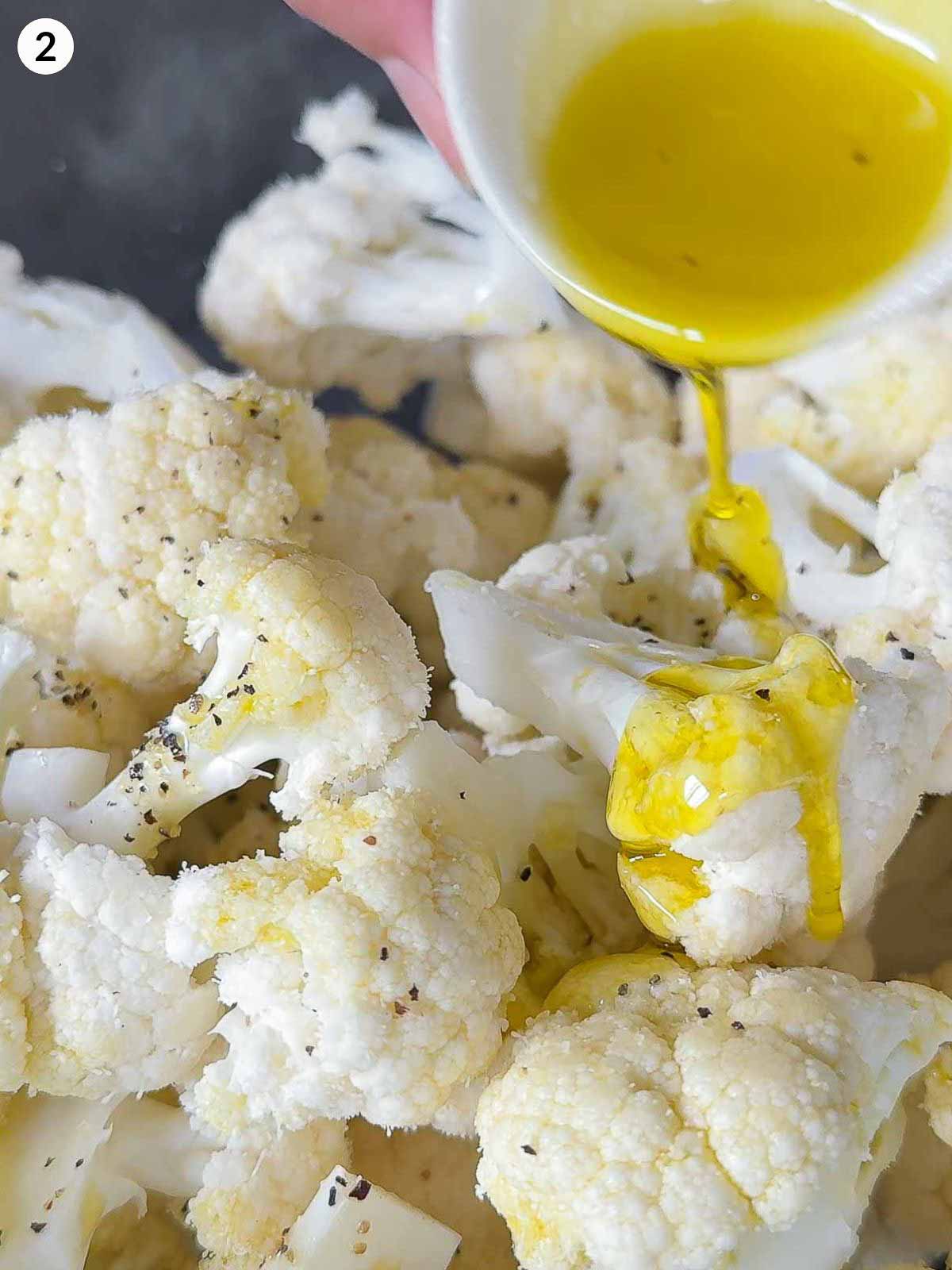 Drizzling olive oil on fresh cauliflower florets — step-by-step guide for roasted cauliflower salad and side dish recipes.