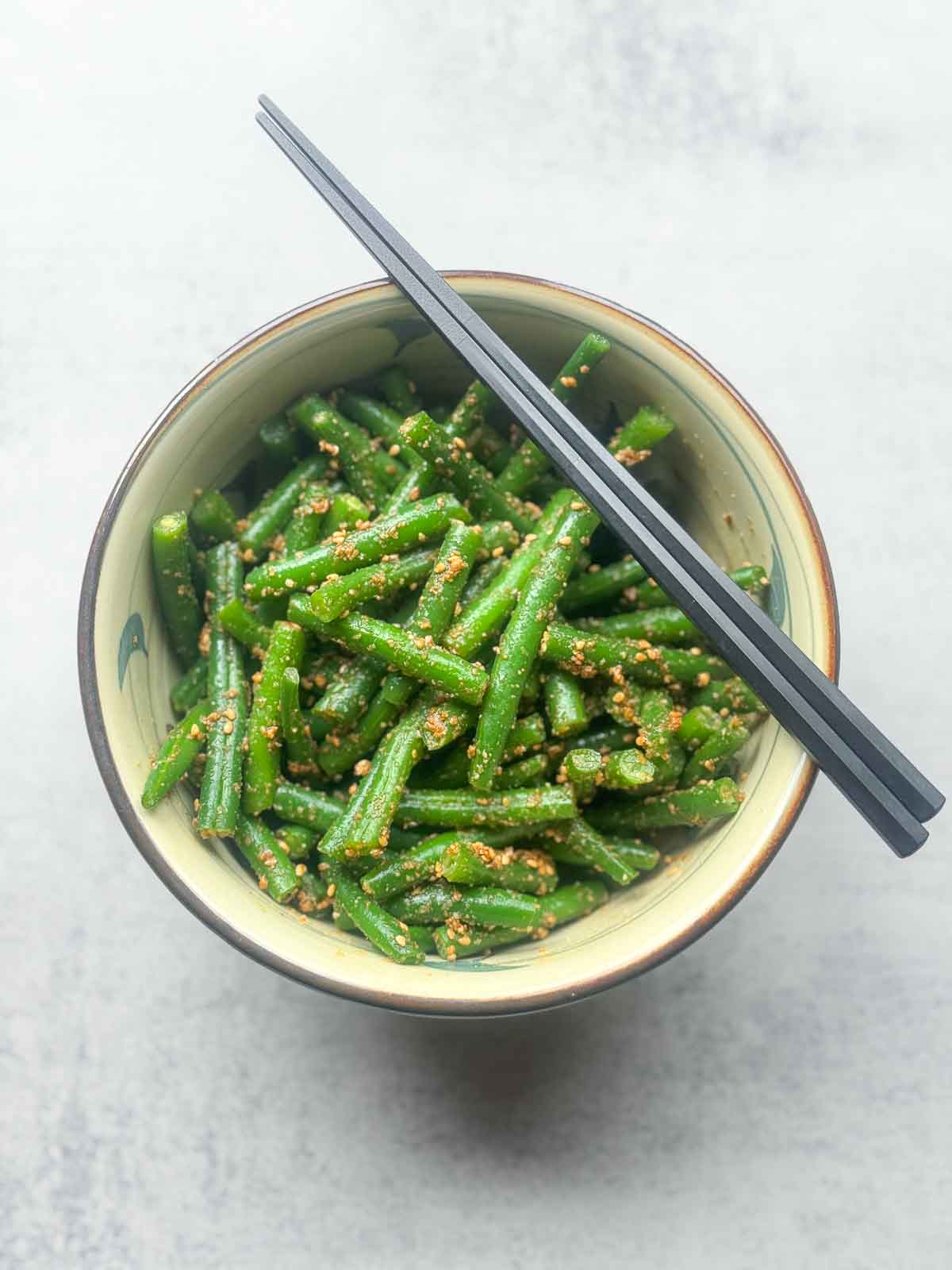 Japanese sesame green beans (green bean Gomaae) served in a ceramic bowl, coated with nutty gomae sesame sauce and sprinkled with ground sesame seeds — a classic Japanese side dish for Asian meals.