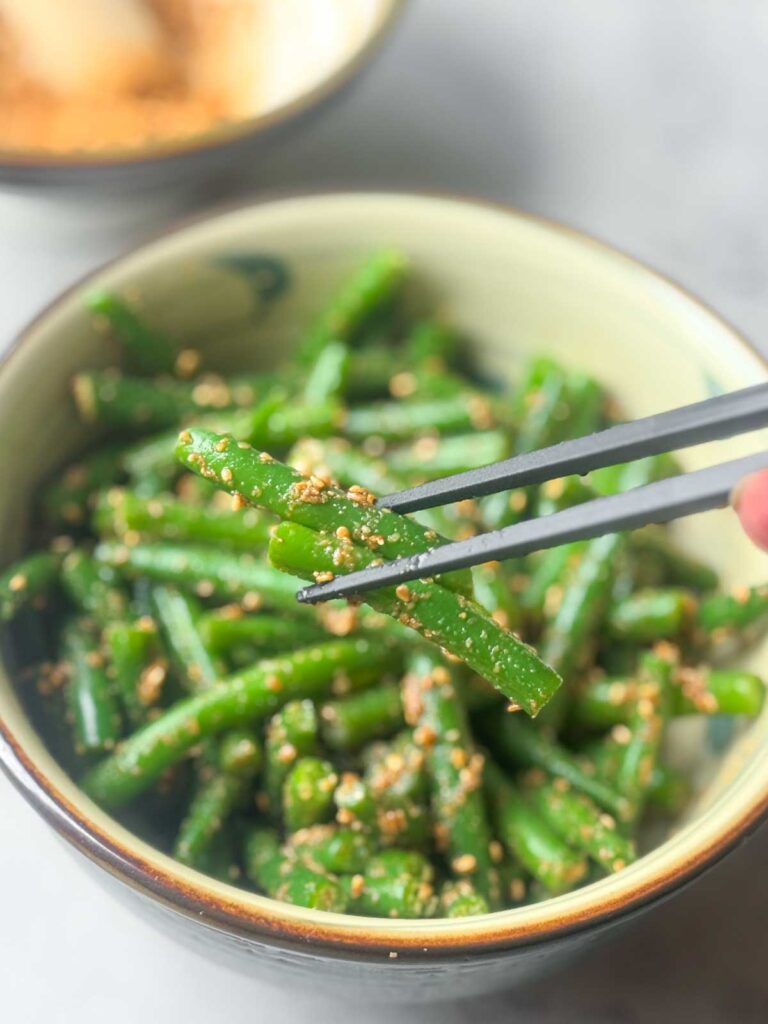 Japanese sesame green beans (green bean Gomaae) served in a ceramic bowl, coated with nutty gomae sesame sauce and sprinkled with ground sesame seeds — a classic Japanese side dish for Asian meals.