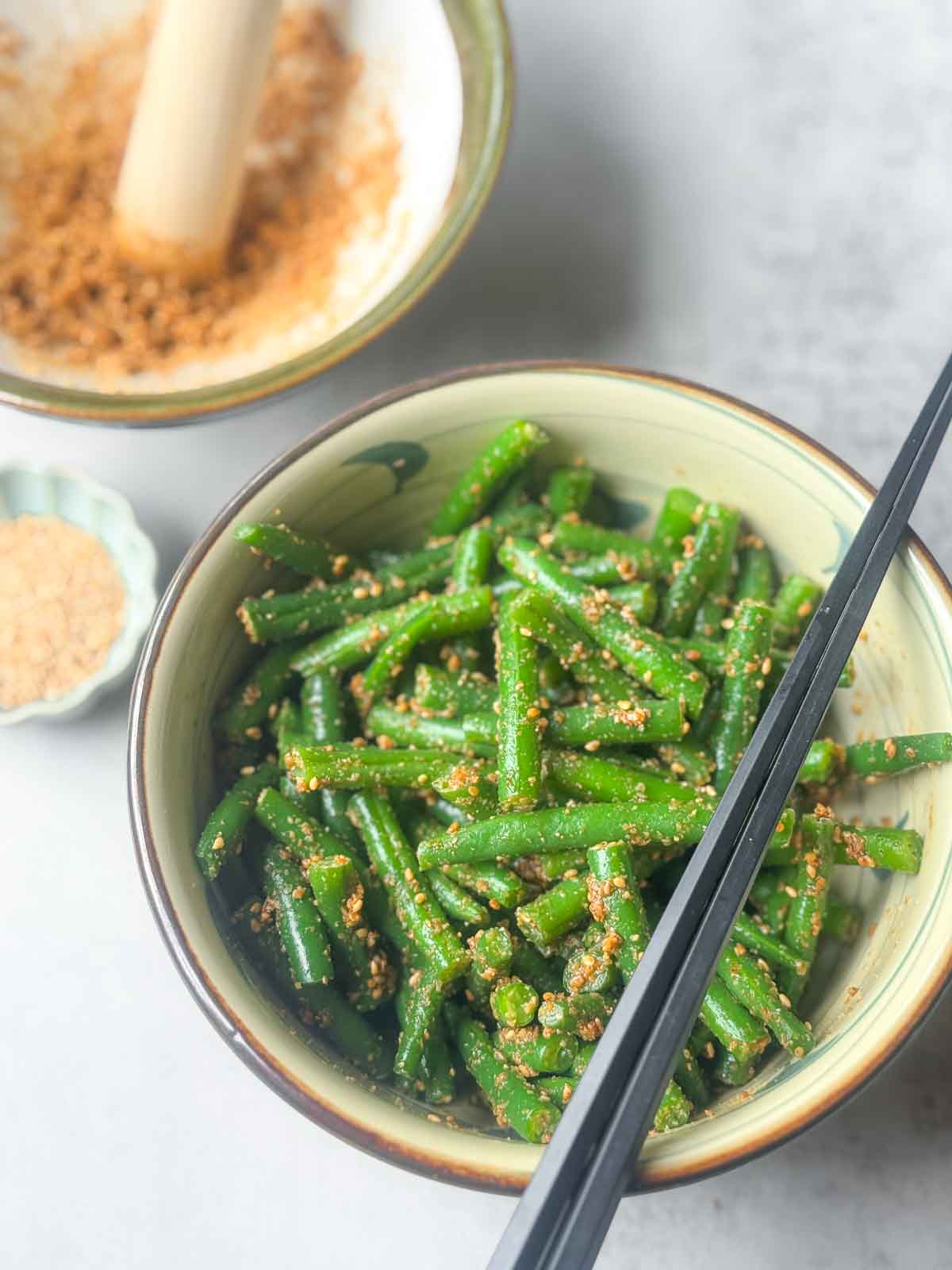 Japanese sesame green beans (green bean Gomaae) served in a ceramic bowl, coated with nutty gomae sesame sauce and sprinkled with ground sesame seeds — a classic Japanese side dish for Asian meals.
