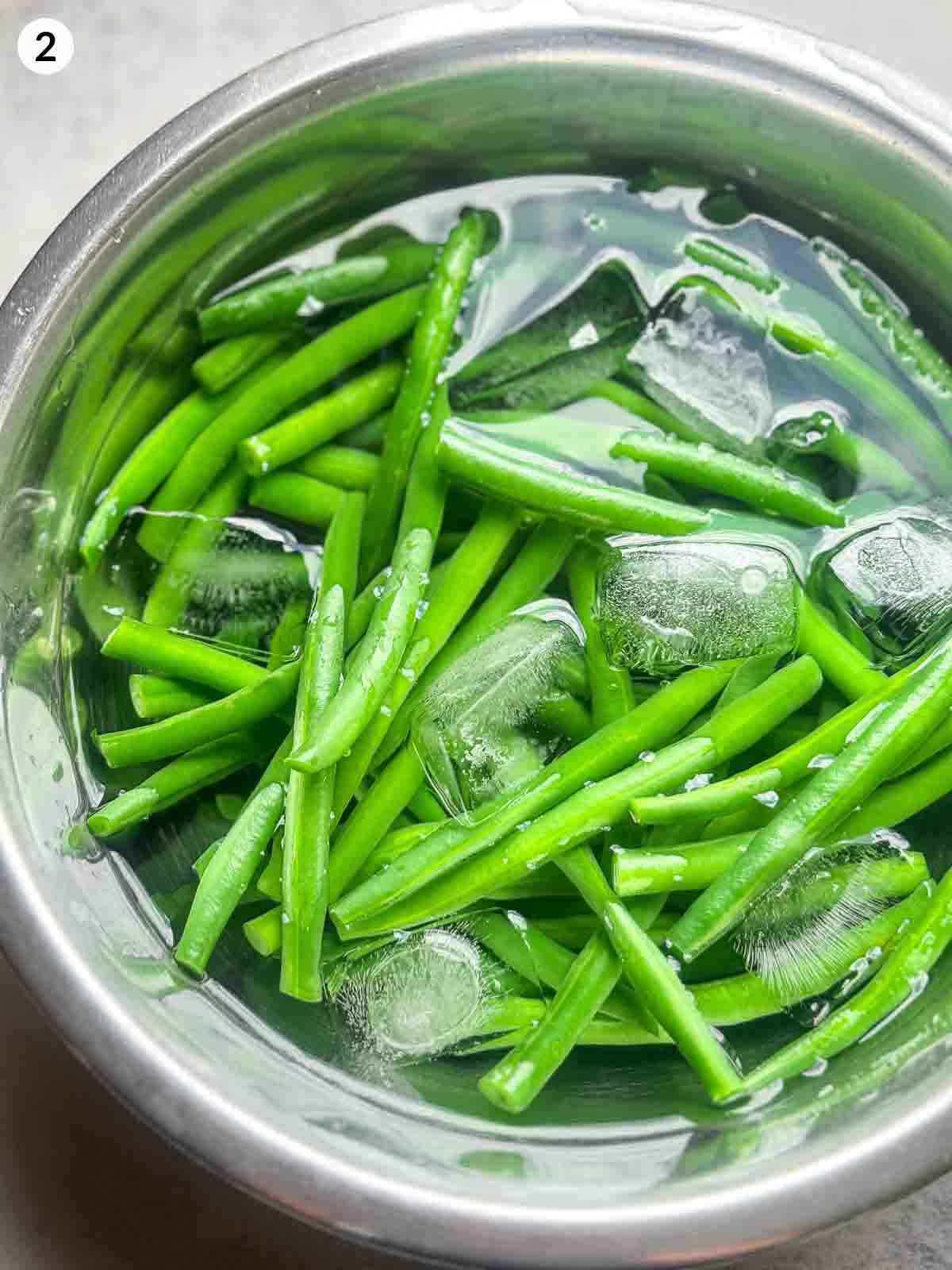 Blanched green beans cooling in an ice bath to lock in colour and crispness before tossing in gomae sesame sauce.