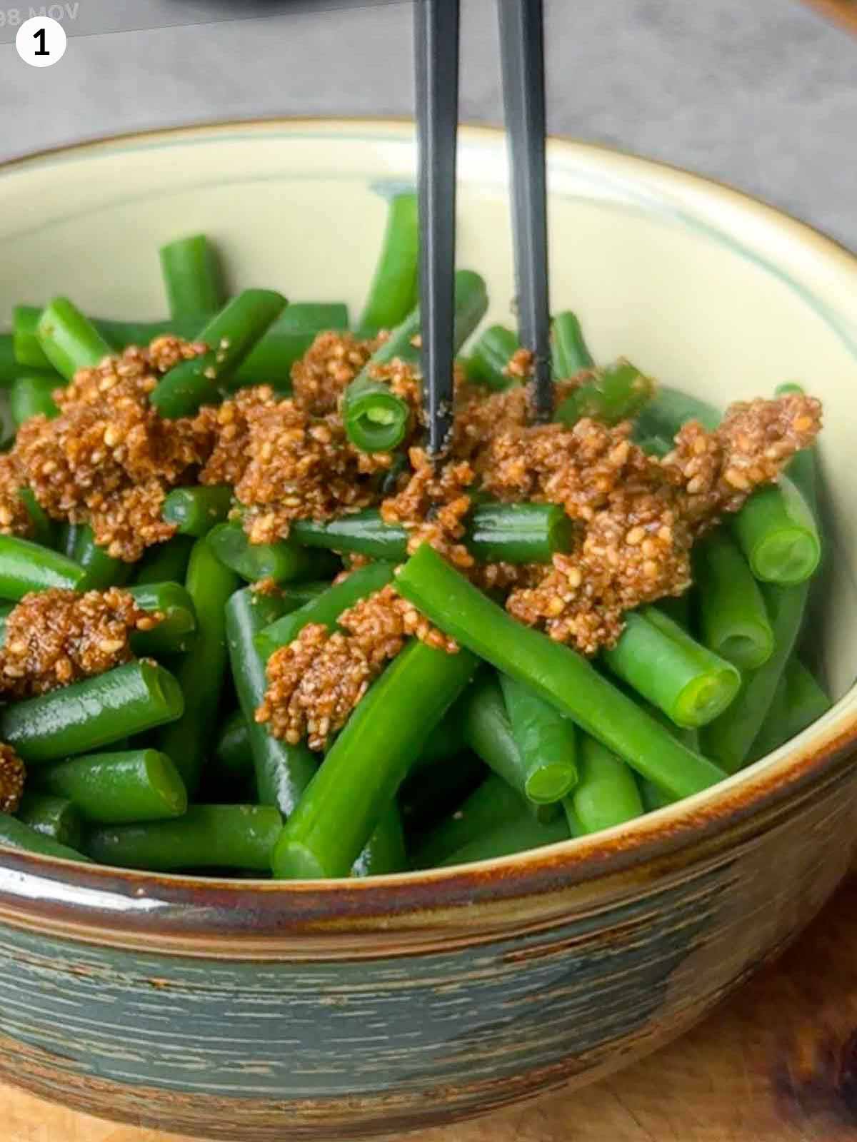 Mixing blanched green beans with thick gomae sesame sauce using chopsticks — the final step for Japanese sesame green beans.