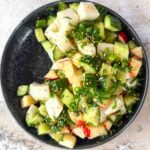 Daikon Cucumber Apple Salad with Togarashi Dressing on a black plate