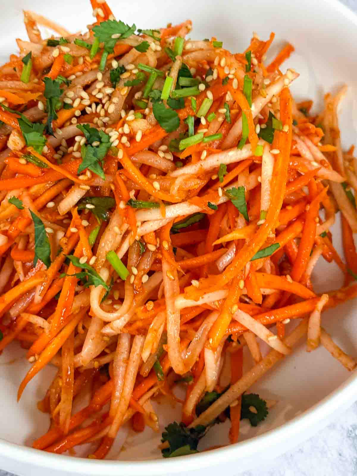 Carrot and Daikon Salad with Gochujang Dressing in a white bowl