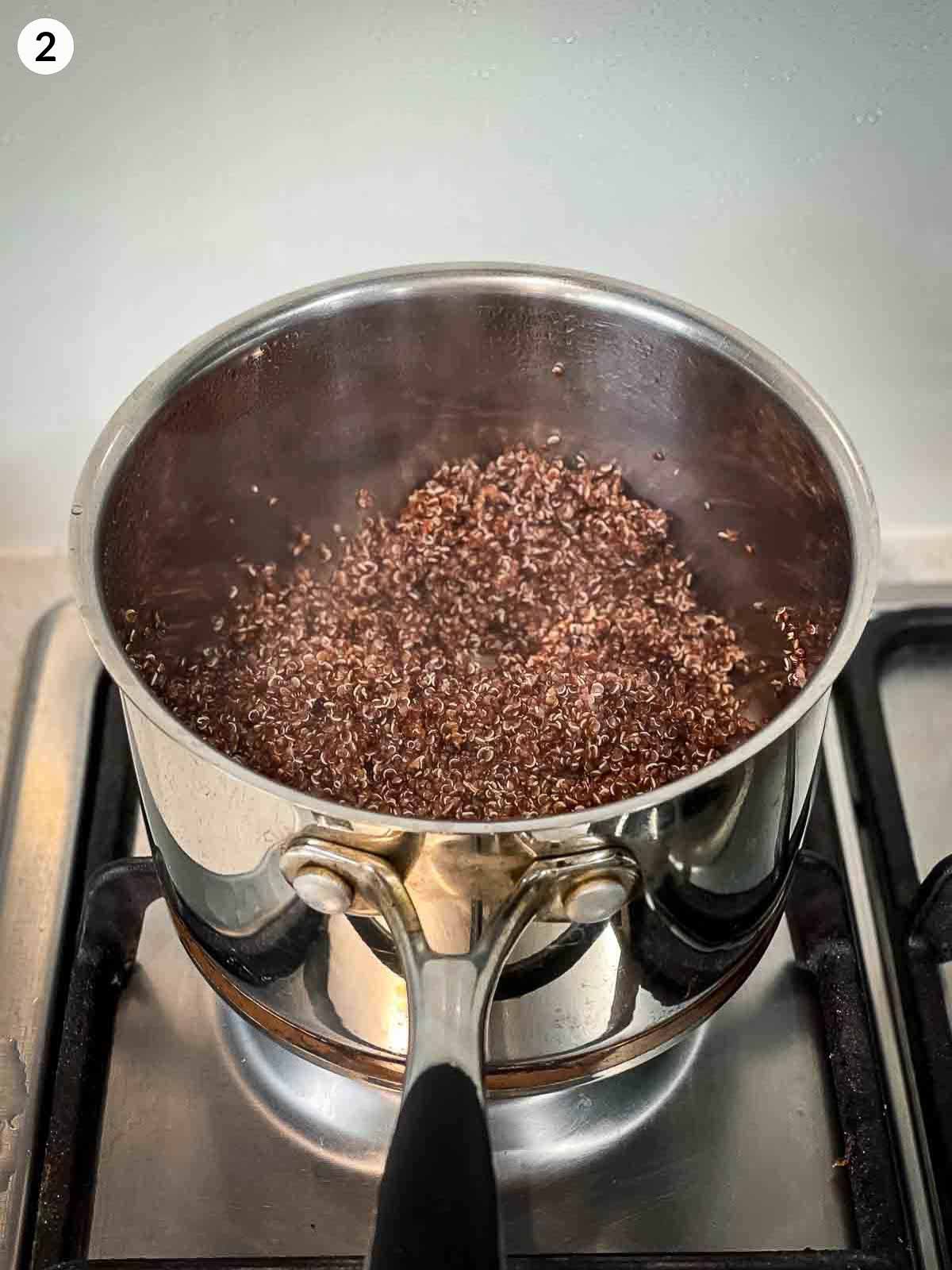 Cooking red quinoa in a stainless steel pot on a cook top