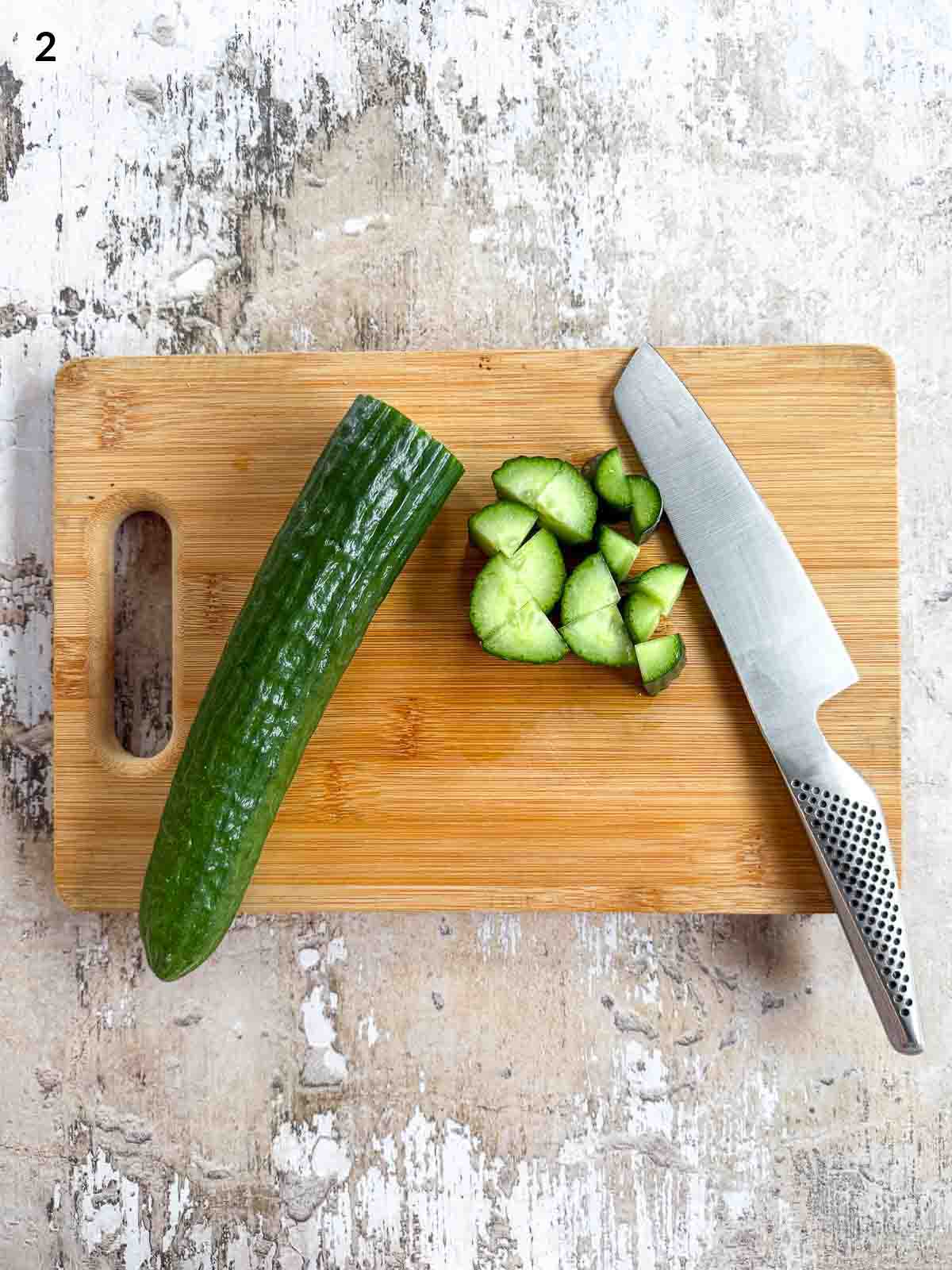 Cutting cucumber with a knife on a wooden chopping board