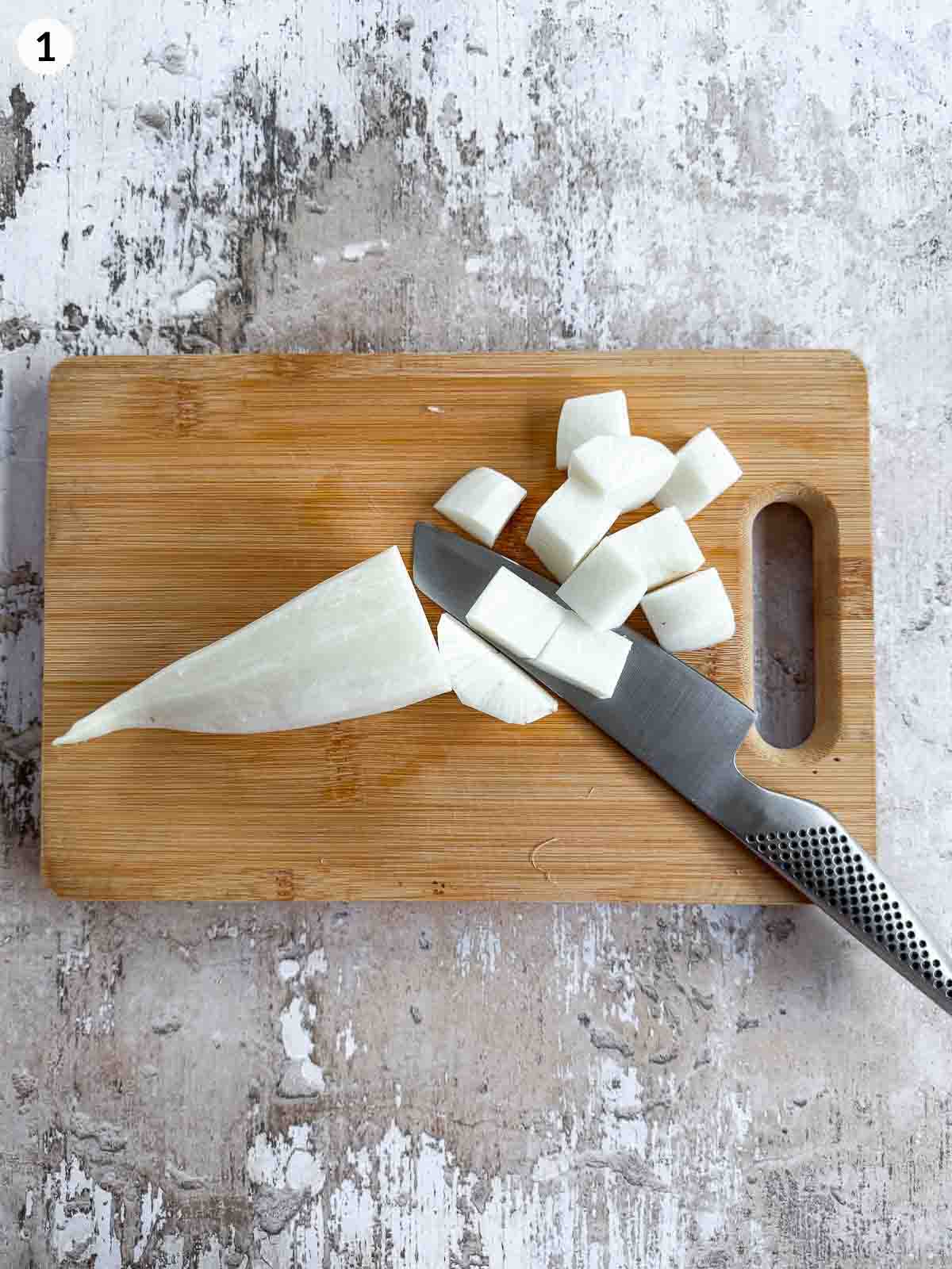 Cutting daikon with a knife on a wooden chopping board