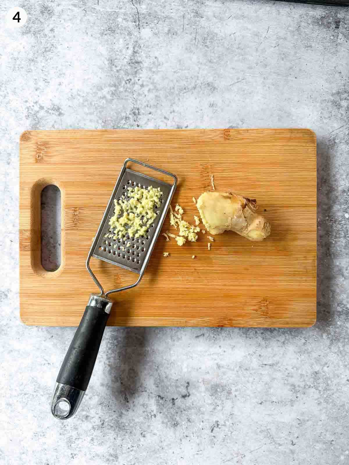 grating ginger on a wooden chopping board with a grater