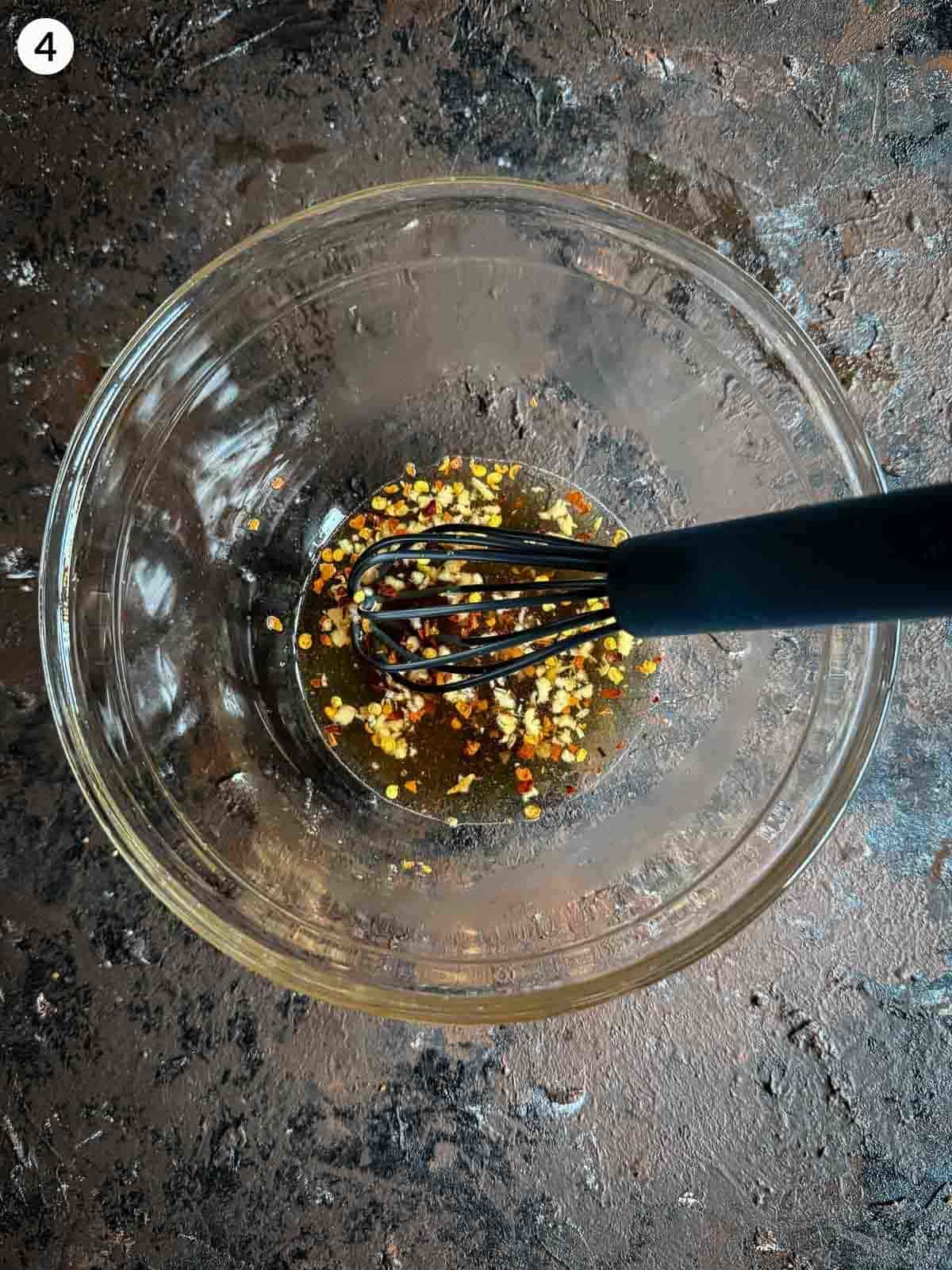 Mixing ingredients for fish sauce salad dressing in a clear mixing bowl with a whisk