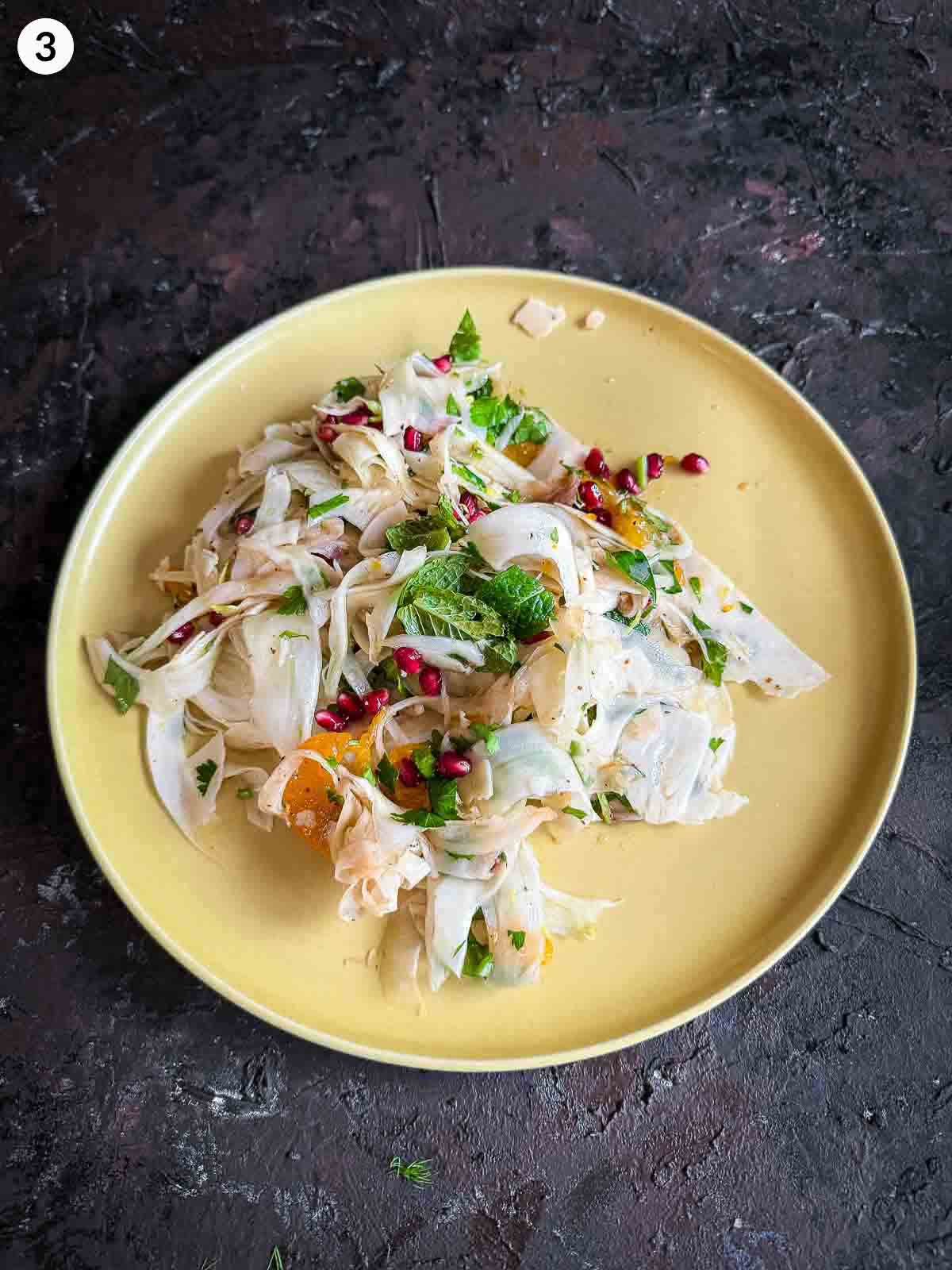 Assembling ingredients for Shaved Fennel Salad with Mandarin, Prosciutto & Pomegranate in a yellow plate
