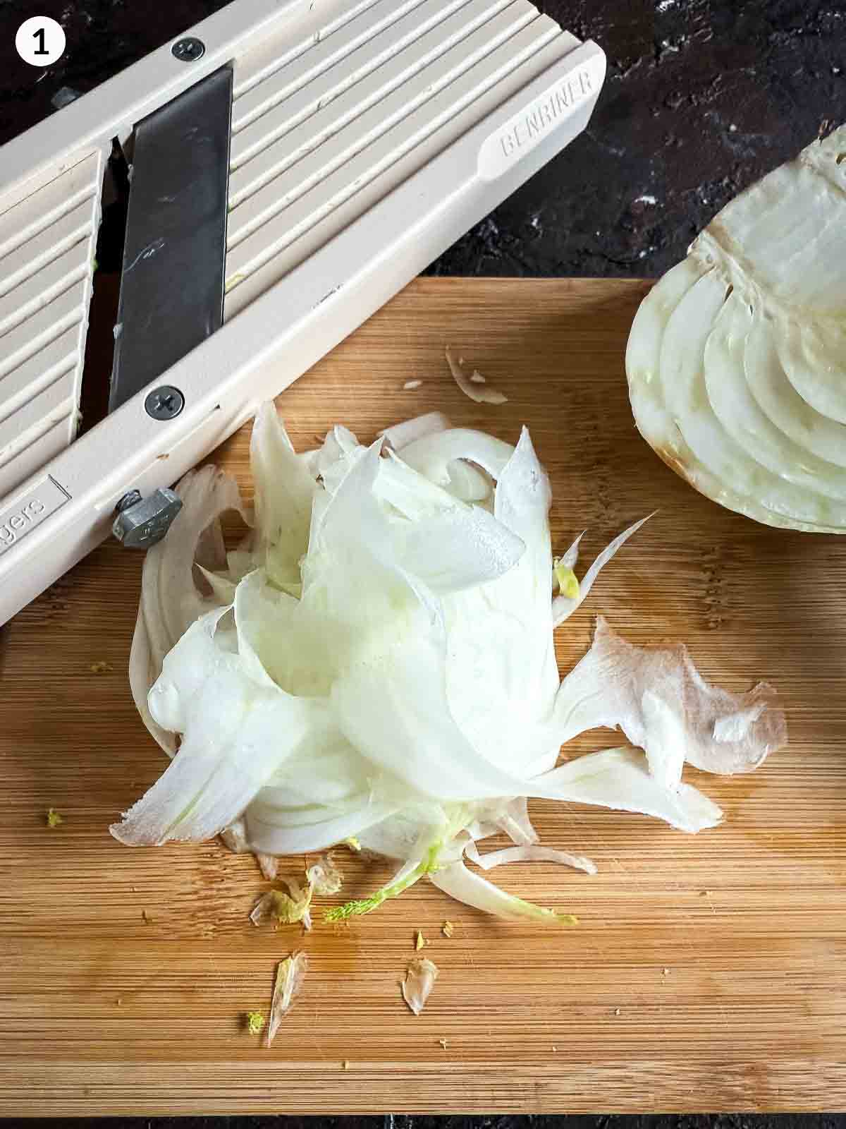 Shaving thin fennel slices with a mandoline on a wooden board