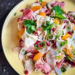 Shaved Fennel Salad with Mandarin, Prosciutto & Pomegranate served on a yellow plate