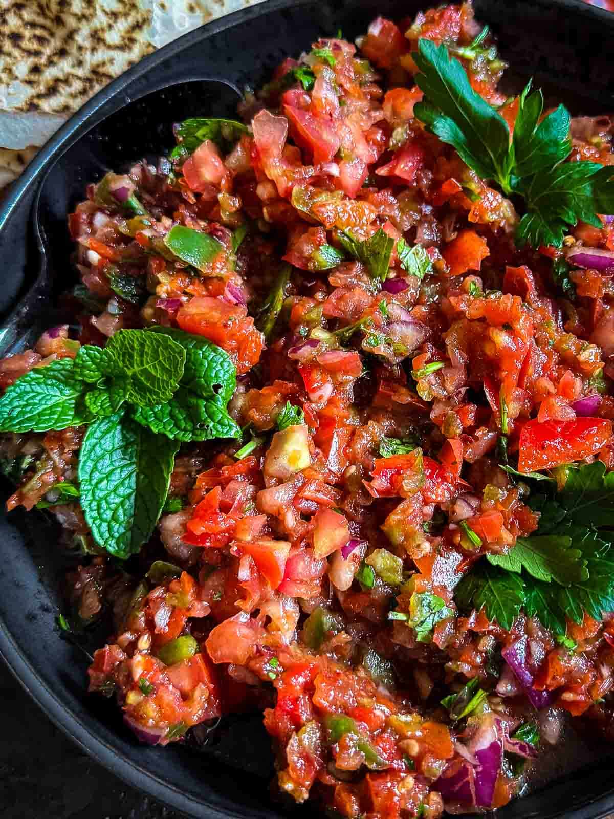 Bowl of Turkish ezme salad in a black plate served with Lebanese bread