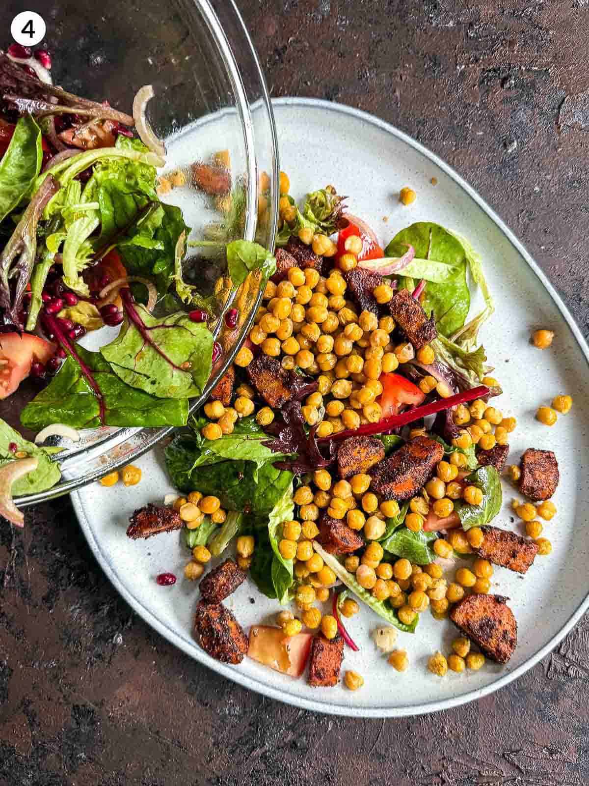 Pouring the ingredients for Roasted Chickpea and Carrot Baharat Salad on a grey platter against a dark background