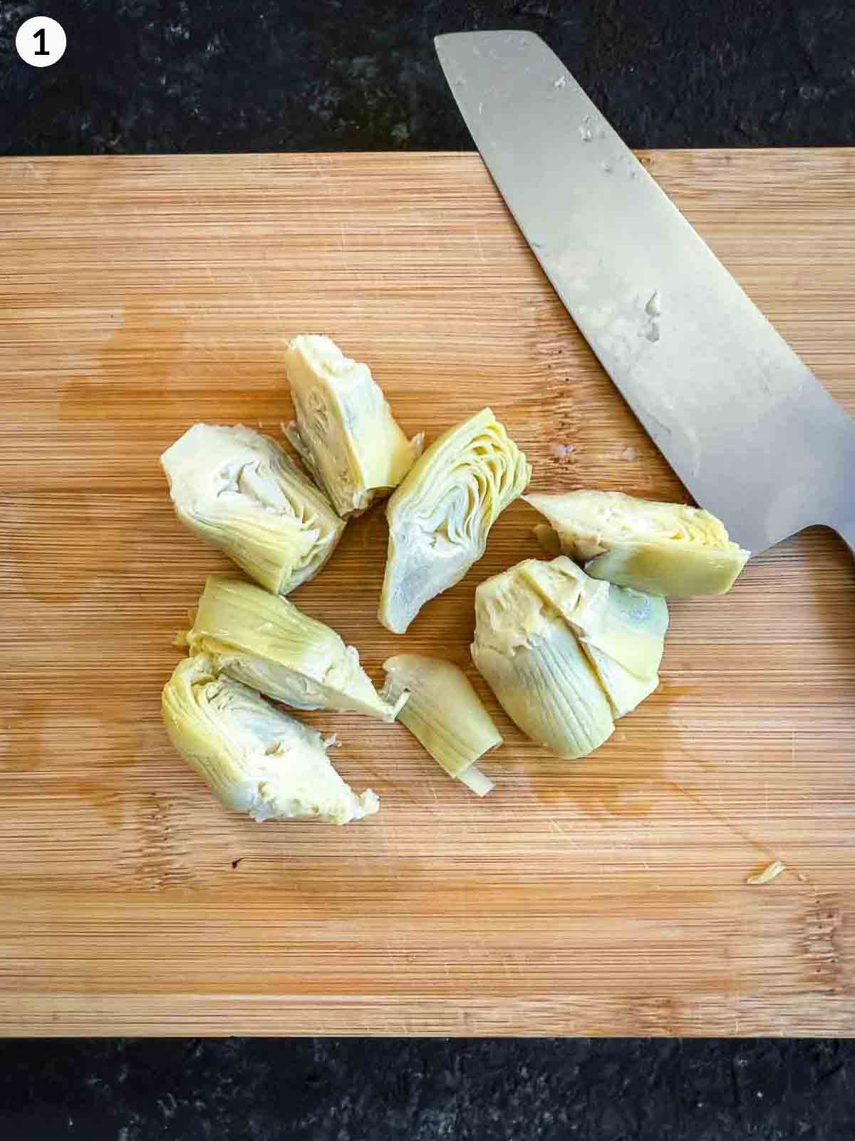 cutting artichoke hearts with a knife on a wooden board
