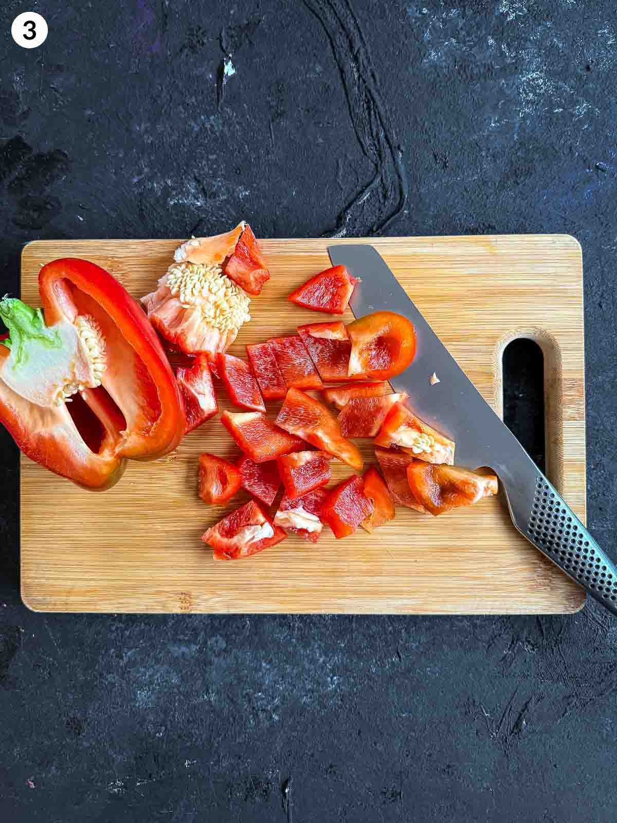 cutting capsicum with a knife on a wooden chopping board