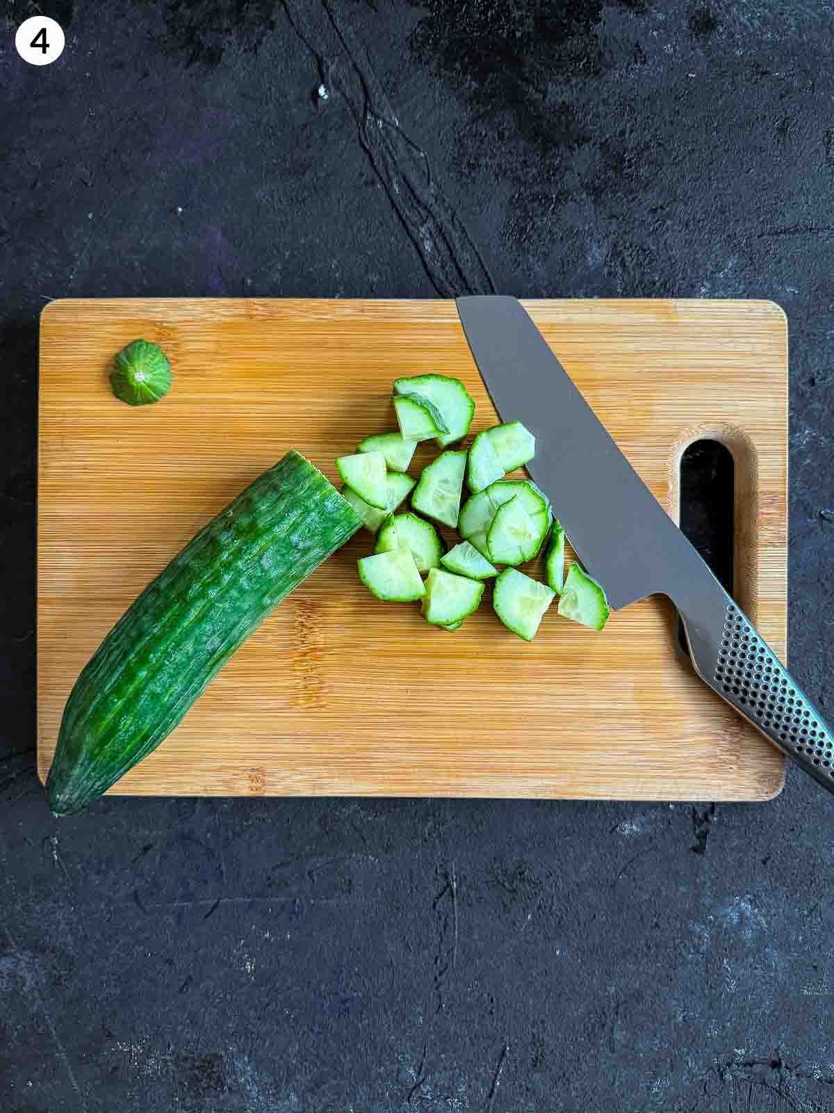 cutting cucumber with a knife on a wooden chopping board