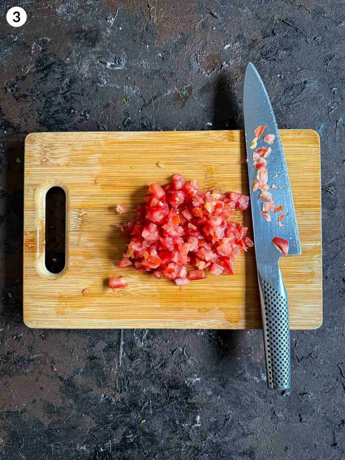 chopping tomatoes with a knife on a wooden board