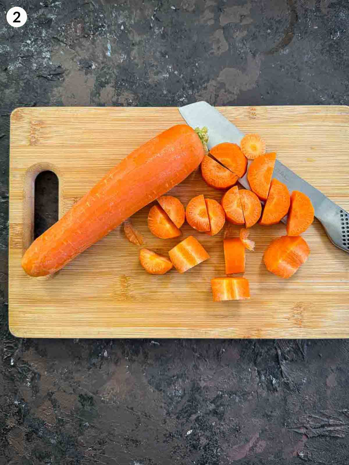 cutting carrots with a knife on a wooden chopping board
